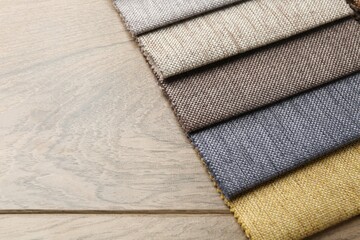 Samples of different fabrics on wooden table, closeup. Space for text