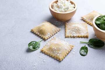 Uncooked ravioli, cottage cheese and spinach on light table, closeup