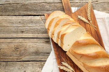 Cut bread loaf and spikes on wooden table, flat lay. Space for text