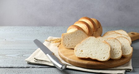Sliced bread and knife on grey wooden table. Space for text