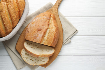 Cut bread loaf on white wooden table, flat lay. Space for text