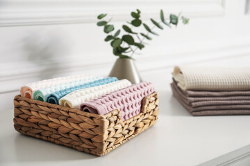 Obraz premium Clean waffle towels and vase with branches on white dresser in bathroom, closeup
