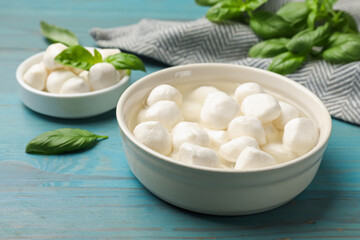 Mozzarella cheese balls and basil on blue wooden table, closeup