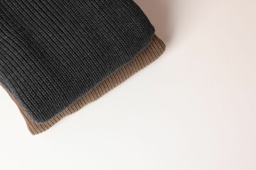 Stack of woolen sweaters on white background, top view. Space for text