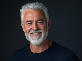Obraz premium Portrait of a smiling senior man with white beard and gray hair, wearing a dark t-shirt. AI generation.