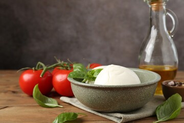 Tasty mozzarella balls, tomatoes, oil and basil on wooden table, closeup