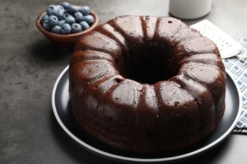 Tasty chocolate bundt cake and blueberries on grey table, closeup