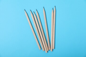 Many graphite pencils on light blue background, flat lay