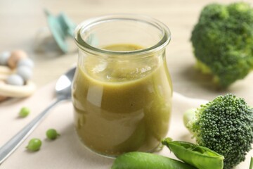Baby food. Tasty puree in glass jar, ingredients and spoon on table, closeup
