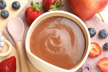 Baby food. Tasty puree in bowl, ingredients and spoon on beige background, flat lay