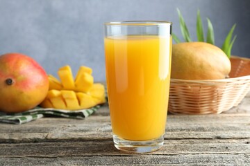 Tasty mango juice in glass and fresh fruits on wooden table