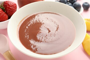 Baby food. Tasty puree in bowl and ingredients on pink background, closeup