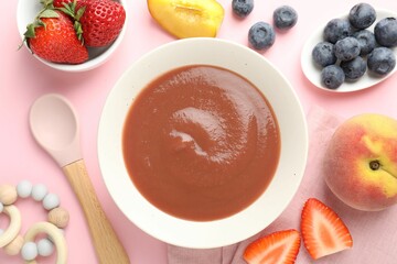 Baby food. Tasty puree in bowl, teether and ingredients on pink background, flat lay