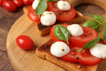 Tasty sandwiches with mozzarella cheese, tomatoes and basil on wooden table, closeup