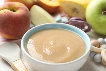 Baby food. Tasty puree in bowl, different ingredients, teether and pacifier on table, closeup