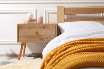 Bedside table with books and decor near bed indoors