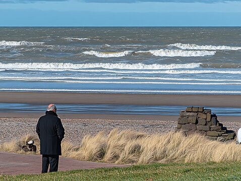 An elderly man watches the ocean on a cloudy day