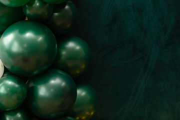Elegant green and dark green balloons on a textured dark emerald green background. Perfect for celebrations, parties, or design backdrops with a luxurious feel.