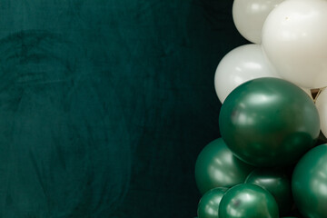 Elegant green and dark green balloons on a textured dark emerald green background. Perfect for celebrations, parties, or design backdrops with a luxurious feel.