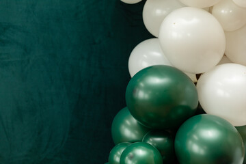 Elegant green and dark green balloons on a textured dark emerald green background. Perfect for celebrations, parties, or design backdrops with a luxurious feel.