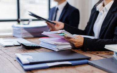 Two busy business professionals man and woman business leaders partners checking document reading financial report talking working together on laptop computer in office at corporate meeting.
