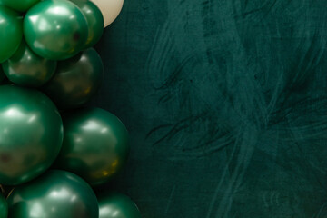 Elegant green and dark green balloons on a textured dark emerald green background. Perfect for celebrations, parties, or design backdrops with a luxurious feel.