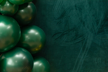 Elegant green and dark green balloons on a textured dark emerald green background. Perfect for celebrations, parties, or design backdrops with a luxurious feel.