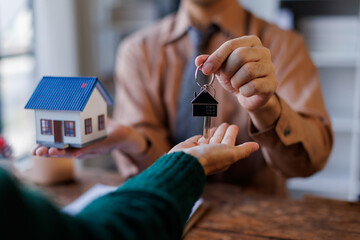 Real estate agent giving house key to the client after signing making sign insurance form...