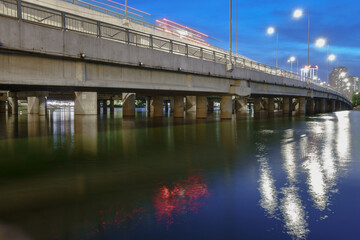 Bridge over water in Linh Dam, Hanoi at dusk showcasing reflections of lights and serene surroundings