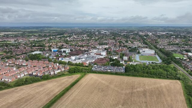 Aerial drone view of Stoke Mandeville Hospital, surrounded by buildings, greenery and cloudy sky