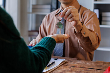 Real estate agent giving house key to the client after signing making sign insurance form...