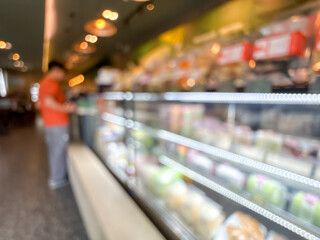 blurry image showing a display case filled with various cakes and pastries. The scene is out of focus