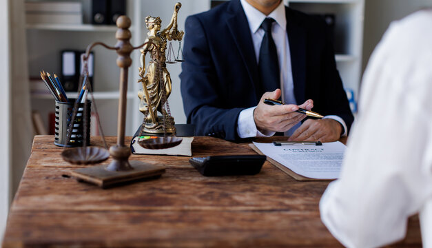 Two lawyers Consultation and conference discussing legal matters at a desk with a gavel, scales of justice law symbolizing law and justice, justice and lawyer Business partnership meeting concept. 
