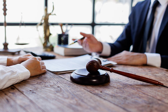 Two lawyers Consultation and conference discussing legal matters at a desk with a gavel, scales of justice law symbolizing law and justice, justice and lawyer Business partnership meeting concept. 
