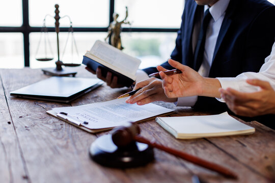 Two lawyers Consultation and conference discussing legal matters at a desk with a gavel, scales of justice law symbolizing law and justice, justice and lawyer Business partnership meeting concept. 
