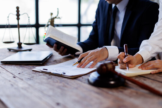 Two lawyers Consultation and conference discussing legal matters at a desk with a gavel, scales of justice law symbolizing law and justice, justice and lawyer Business partnership meeting concept. 
