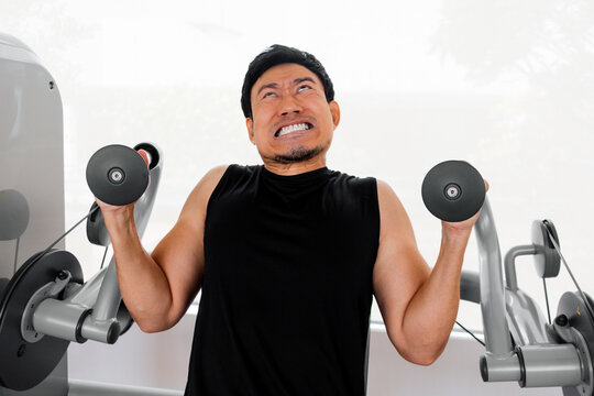 Man struggling with dumbbell curls during strength training