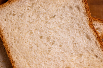 Two slices of garlic bread, their grease minimal, on a wooden board with a subtle shine.