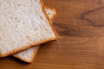 Two slices of garlic bread, their grease minimal, on a wooden board with a subtle shine.