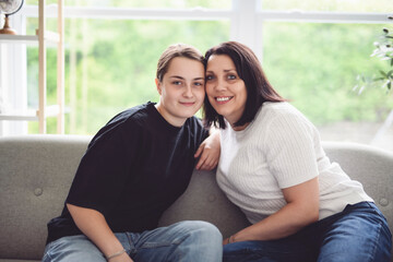 mother with teen girl, having great time on sofa