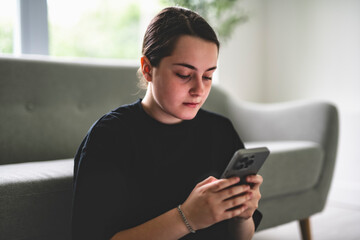 15 years old teen girl sit on sofa at home with cellphone