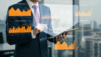 Businessman in a suit, holding a tablet with holographic data projections, in an office setting - Powered by Adobe