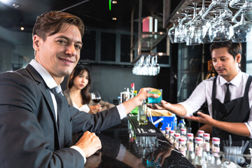 Handsome office man drinking cocktail in rooftop bar after work with female coworker
