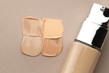 Colorful skin foundations and bottle on grey background, flat lay