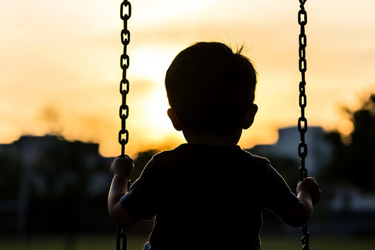Child on a swing enjoying the sunset at a park