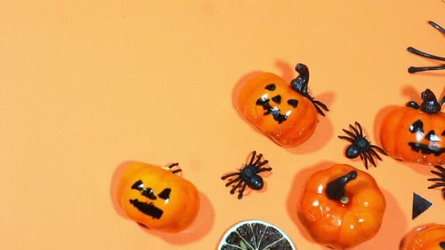 Halloween frame with party decorations of pumpkins, bats, ghosts, spiders on orange background from above. Happy halloween card in flat lay style.
