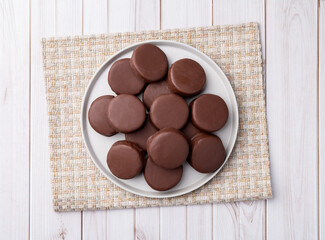 Brazilian Pao de Mel or chocolate covered honey cookies over a wooden table