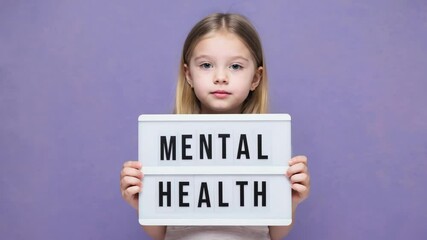 Girl holding mental health text sign with purple background, raising awareness about emotional well-being, psychology, and support for children