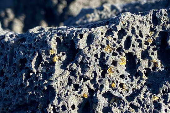 Olivine gemstones included in black lava basalt rock in Tenerife,Canary Islands,Spain.Peridot crystals.
Selective focus.