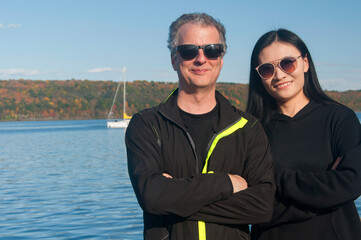 a couple with crossed arms in front of Cayuga lake new york